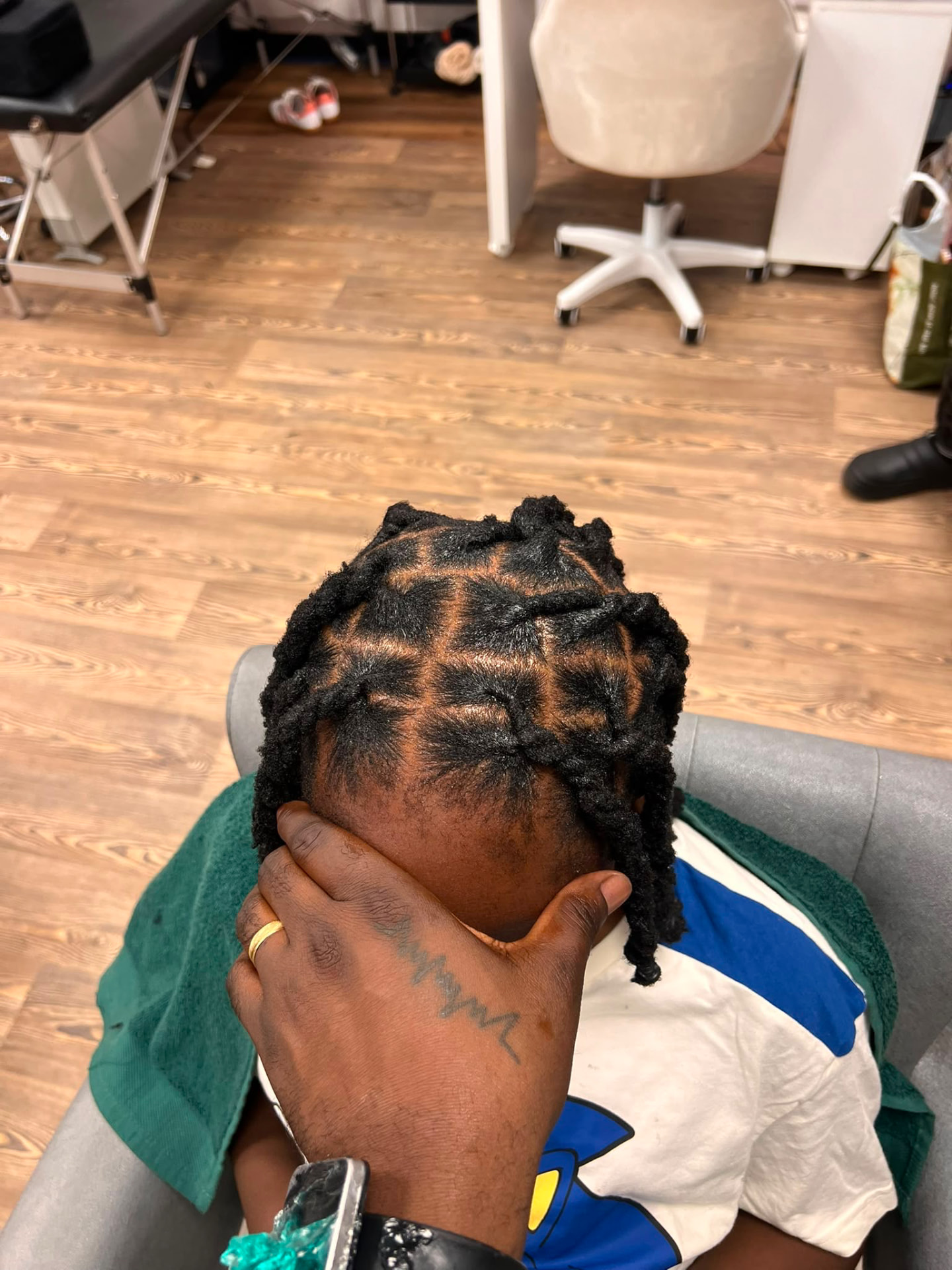 Short loc retwist with clean square parting on a male client