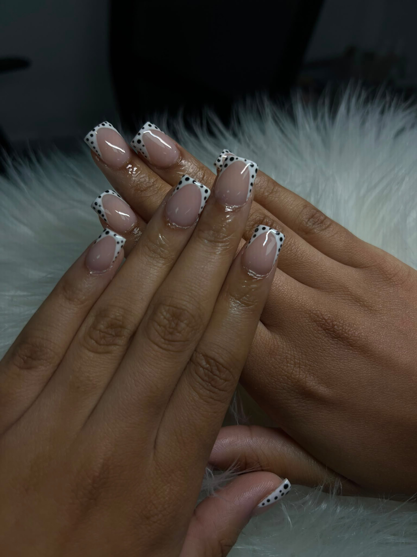 French-tip nails with black polka-dot detail